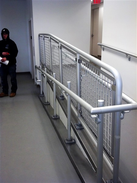 Indoor gray/silver pipe railing between handicap ramps