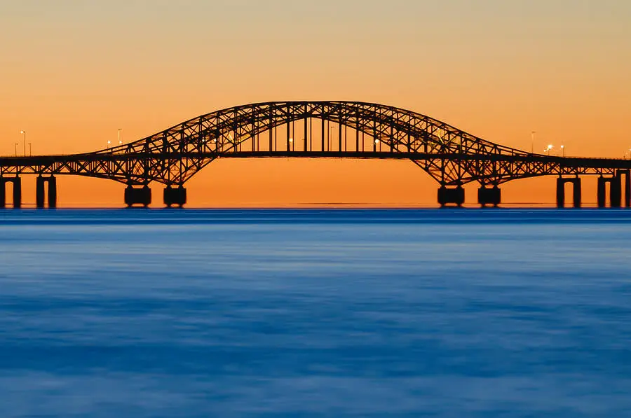 Distant view of bridge over water during sunset